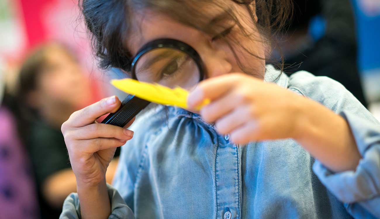 Young child looking through magnifying glass