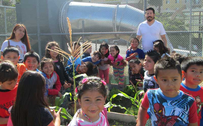 Group photo of young children surrounding a garden